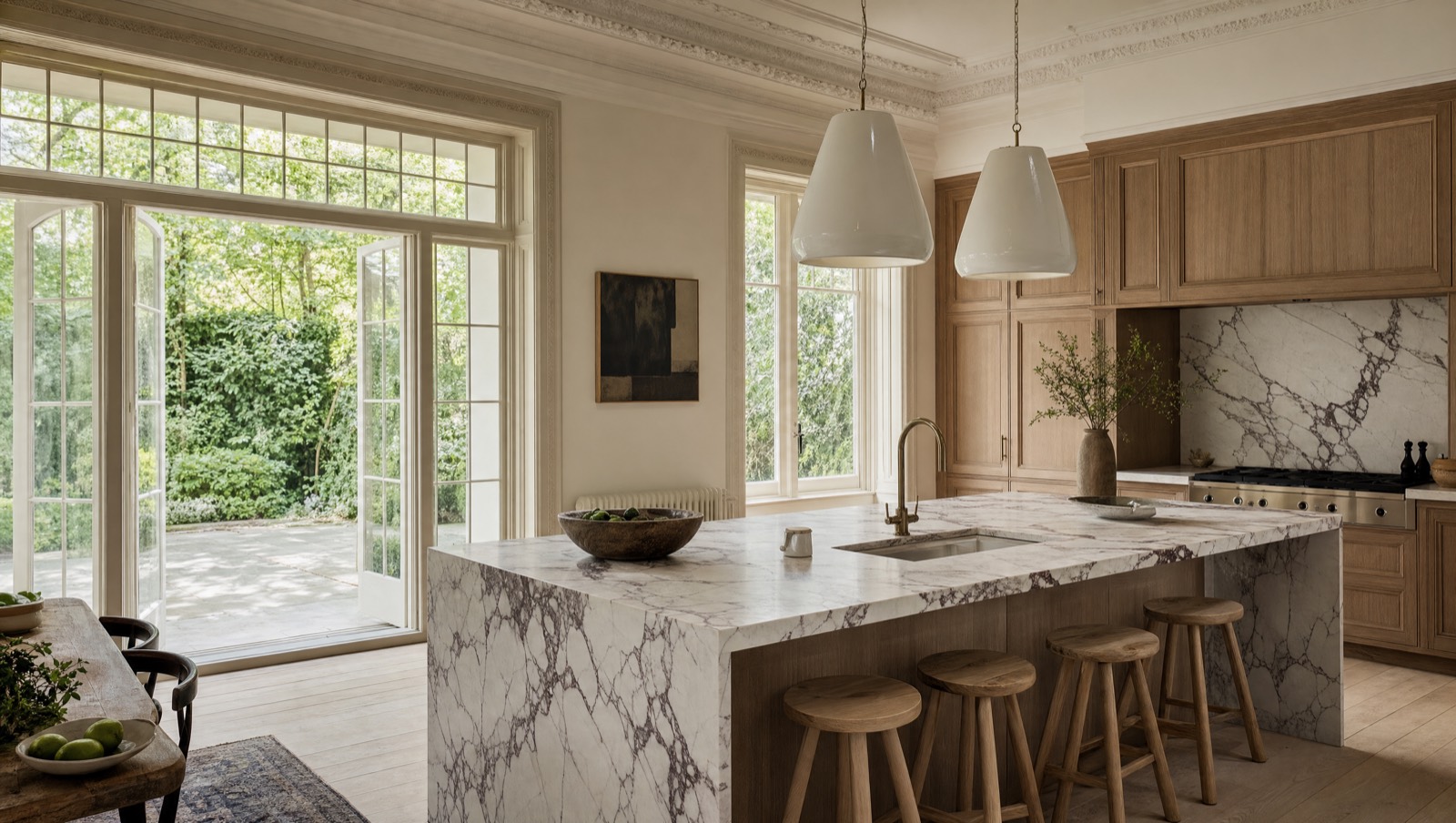 A large marble kitchen island in a light-filled kitchen with high ceilings and garden doors